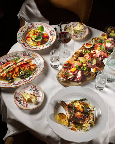 En klassisk italiensk måltid på Capannone bestående av: italienska charkuterier, caprese på buffelmozzarella och datterinitomater, linguine med skaldjur, tomat, fänkål och vitt vin, milanesisk kalvschnitzel med ramslökssmör och friterad kapris.